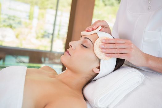 Peaceful brunette getting facial from beauty therapist in the health spa