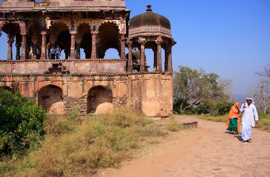 Indian man and woman walking along old temple, Ranthambore Fort, Rajasthan, India