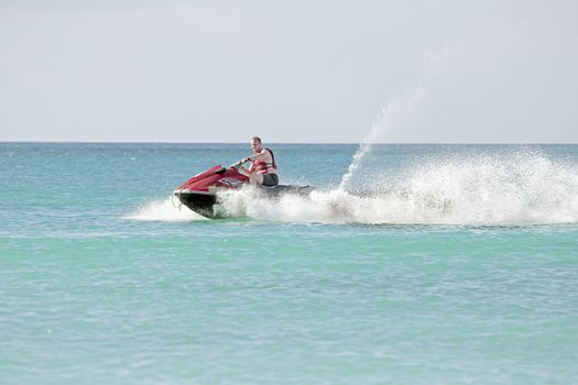 Young guy cruising on the caribbean sea on a jet ski