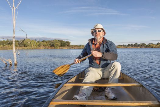 senior male enjoying morning sun on lake in a canoe, Riverbend Ponds Natural Area, Fort Collins, Colorado