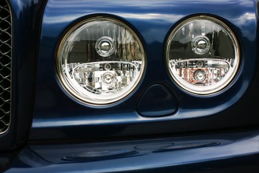 Forward part of the case of the prestigious car of dark blue colour with headlights.