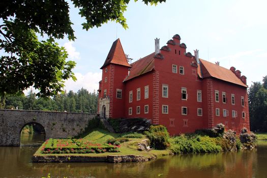 Photo shows red castle house and its surroundings.