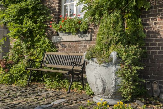 old farm with green plants on the wall and seat and vase with plants on the old rocks in the garden