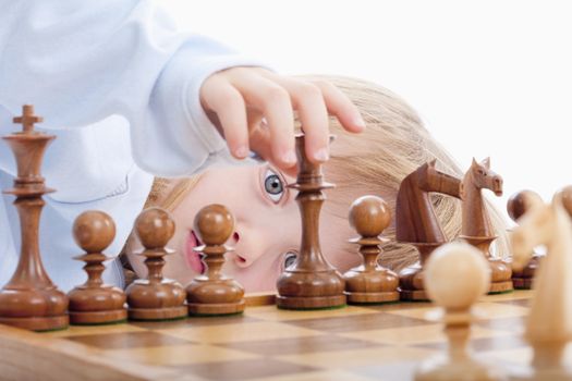 boy with long blond hair playing with chess pieces - isolated on white