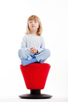 boy with long blond hair sitting on a red stool - isolated on white