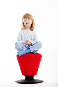 boy with long blond hair sitting on a red stool - isolated on white