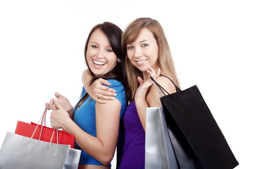 two happy young girls with shopping bags smiling - isolated on white