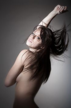 beautiful nude woman with dark hair standing - isolated on gray