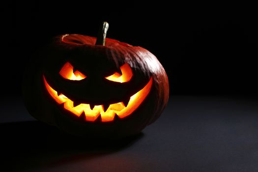 Halloween pumpkin head jack lantern with scary evil face on black