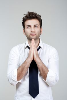 businessman in white shirt and tie holding hands together, praying - isolated on gray