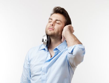 man in blue shirt with earphones listening to music - isolated on white