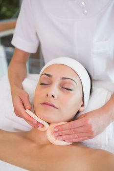 Peaceful brunette getting facial from beauty therapist in the health spa