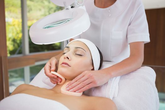 Peaceful brunette getting facial from beauty therapist in the health spa