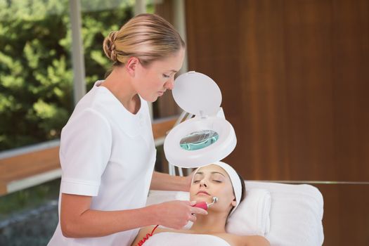 Peaceful brunette getting micro dermabrasion from beauty therapist in the health spa