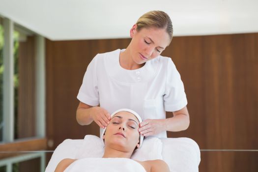 Peaceful brunette getting facial massage from beauty therapist in the health spa