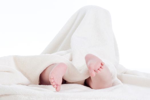 baby wrapped in white towel with its feet skicking out