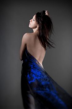 beautiful nude woman with dark hair in blue cloth - isolated on gray