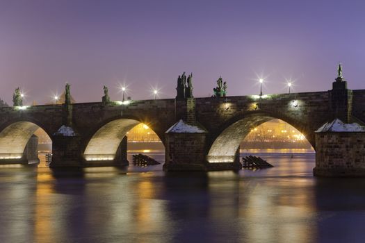 czech republic prague - illuminated charles bridge at dusk in winter