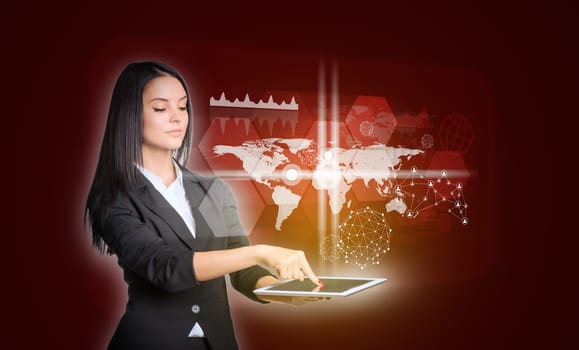 Beautiful businesswomen in suit using digital tablet. World map with transparent hexagons, graphs and network