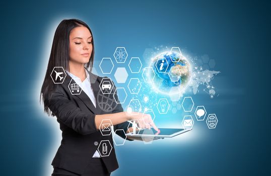 Beautiful businesswomen in suit using digital tablet. Earth and transparent hexagons with icons. Element of this image furnished by NASA