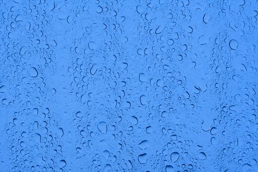closeup of waterdrops after rain on glass roof reflecting blue sky