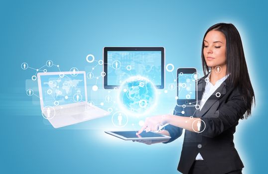 Beautiful businesswomen in suit using digital tablet. Earth with laptop, tablets and smartphone. Element of this image furnished by NASA