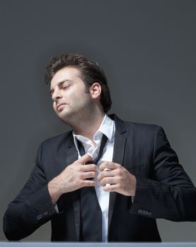 businessman in suit loosening up his tie - isolated on gray