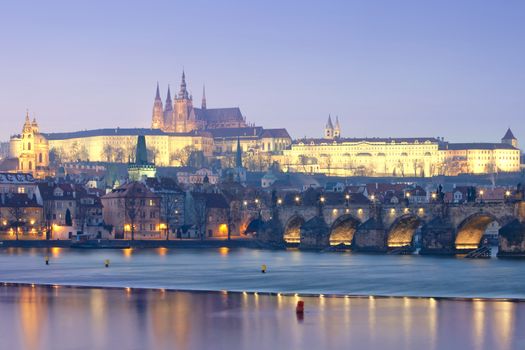 prague in winter - charles bridge and hradcany castle at dusk