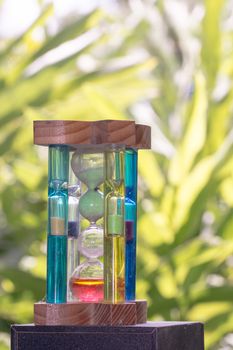 gorgeous hourglass on the green blur background symbolizing a short time of vacation
