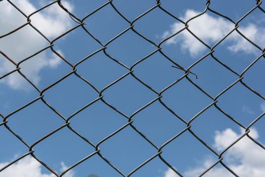 Metal mesh wire fence with blur cloud and blue sky background