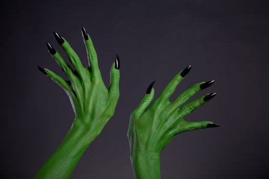 Green monster hands with black nails, Halloween theme, studio shot on black background 