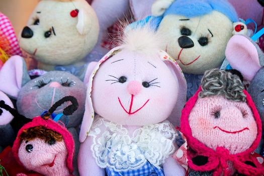 The souvenirs in the form of amusing dolls sewed from rags of fabric and laces. Are presented on a beautiful background with an embroidery.