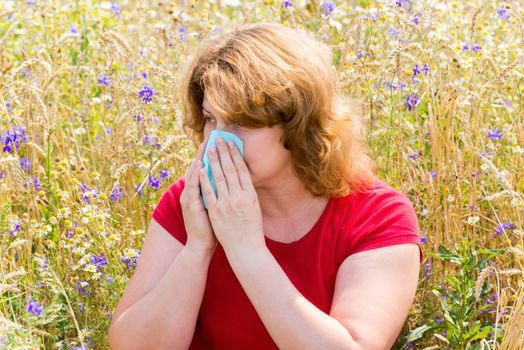 Fat woman with allergic rhinitis in the meadow