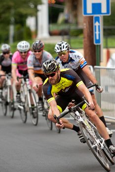 Duluth, GA, USA - August 2, 2014:  A group of cyclists race into a turn on a downtown Duluth street as they compete in the Georgia Cup Criterium event.