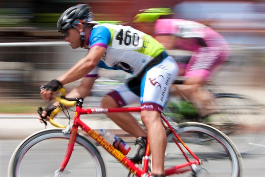 Duluth, GA, USA - August 2, 2014:  Colorful motion blur of two cyclists speeding by as they compete in the Georgia Cup, a criterium event held on the streets of downtown Duluth.