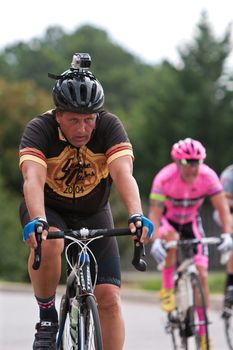 Duluth, GA, USA - August 2, 2014:  A male cyclist wearing a Go Pro helmet cam races down a Duluth street as he competes in the Georgia Cup Criterium event.