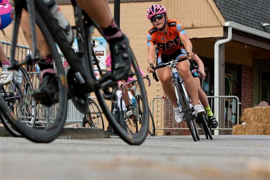 Duluth, GA, USA - August 2, 2014:  A group of female cyclists race into a turn on a downtown Duluth street as they compete in the Georgia Cup Criterium event.