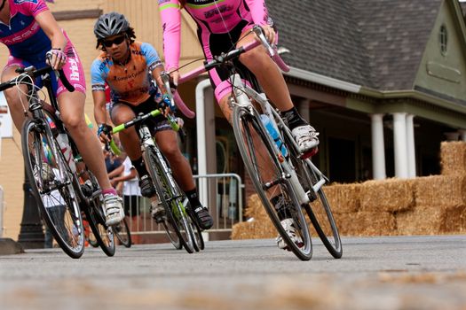 Duluth, GA, USA - August 2, 2014:  Low-angle perspective of a group of female cyclists racing into a turn on a downtown Duluth street as they compete in the Georgia Cup Criterium event.