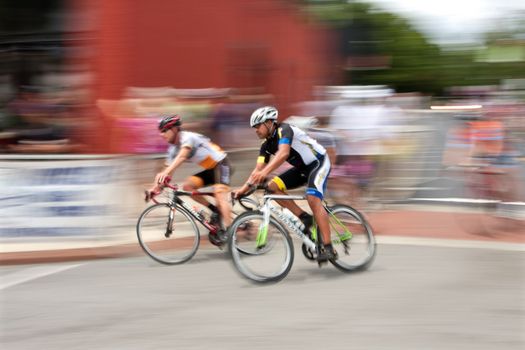 Duluth, GA, USA - August 2, 2014:  Colorful motion blur of two cyclists speeding by as they compete while racing in the Georgia Cup, a criterium event held on the streets of downtown Duluth.