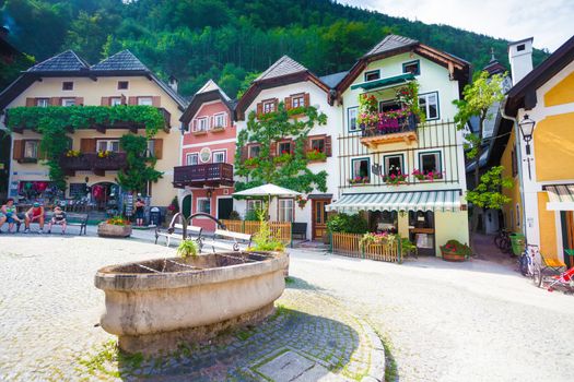 Hallstatt, Austria - August 7, 2013: Public drinking water fountain with typical colorful houses in Hallstatt village, Austria