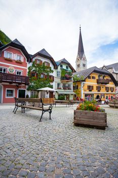 Hallstatt, Austria - August 7, 2013: Colorful houses village square with church bell tower in background, Hallstatt, Austria
