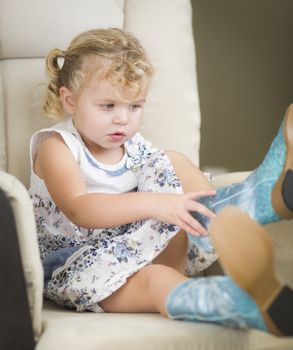 Adorable Blonde Haired Blue Eyed Little Girl Putting on Cowboy Boots.