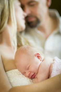 Beautiful Young Couple Holding Their Newborn Sleeping Baby Girl Inside.