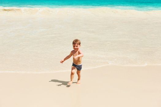 Two year old baby boy playing on beach at Seychelles