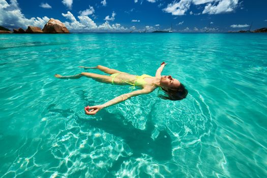 Woman in bikini lying on water at tropical beach