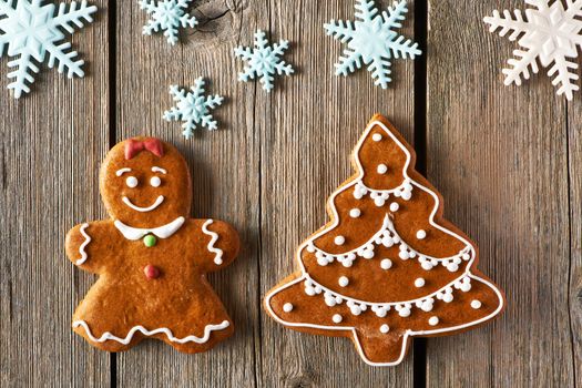 Christmas homemade gingerbread girl and tree on wooden table