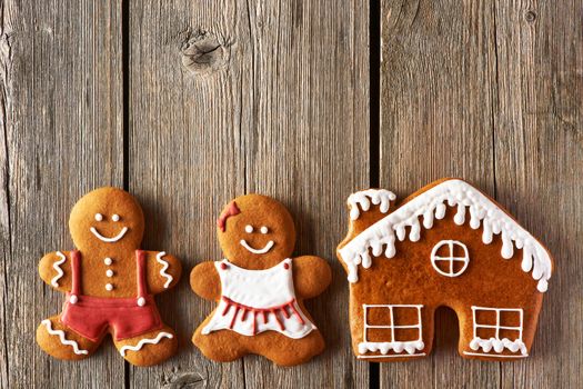 Christmas homemade gingerbread couple and house on wooden table