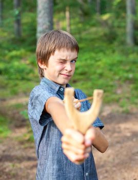 Boy aiming wooden slingshot outdoors