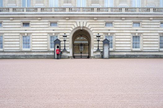 A lonely Queen's guard standing in front of Buckingham Palace gates in London, UK
