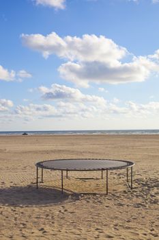 Empty trampoline at beach with blue sky